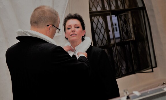 Billede af mandlig præst, der giver kvindelig præst præstekrave på